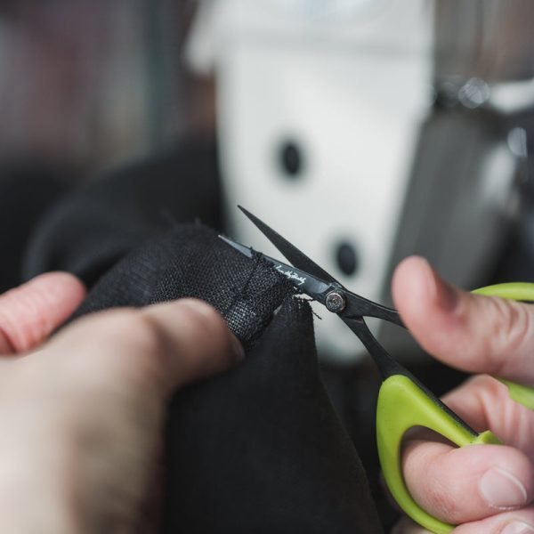Tailoring shears cutting a length of dark cloth