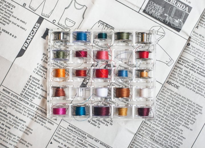 Tray of coloured thread bobbins beside cutting shears