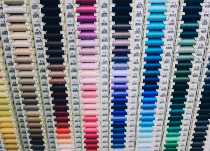 Rows of thread spools graded by colour on a workroom wall
